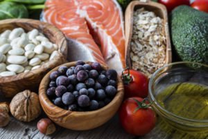 An image of anti-ageing superfoods, including salmon, blueberries, olive oil, avocado, oatmeal and tomatoes