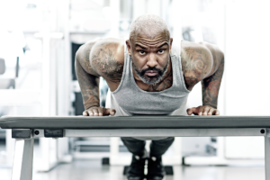 building muscle mass at 40 - An image of a middle aged man doing press ups on a bench in the gym.