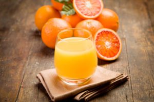 image of fresh orange juice and oranges on a wooden table for an article about 7 foods for healthy eyes