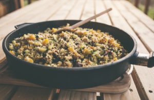 Autumnal quinoa salad with pumpkin and vegetables in frying pan, served outdoors.
