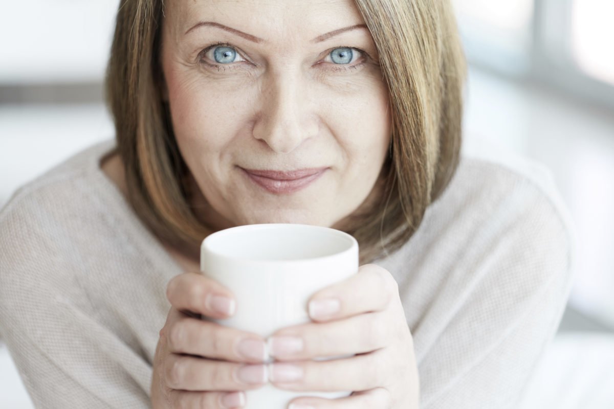 image of a woman looking at the camera with a mug for an article about 7 foods for healthy eyes
