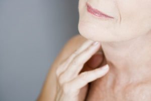 image of an older woman with wrinkles touching her neck for an article about facial exercises for jowls