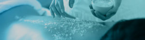 A cropped image of a body exfoliation spa treatment with a blue tint.