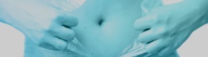 A cropped image of a woman holding her stomach with a blue tint.