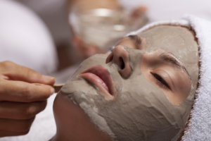 An image of a woman with a clay mask on her face.