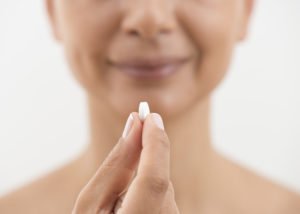 Image of a woman holding a nutrient supplement.