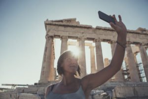 An image of a mature Woman taking a selfie in front of Parthenon
