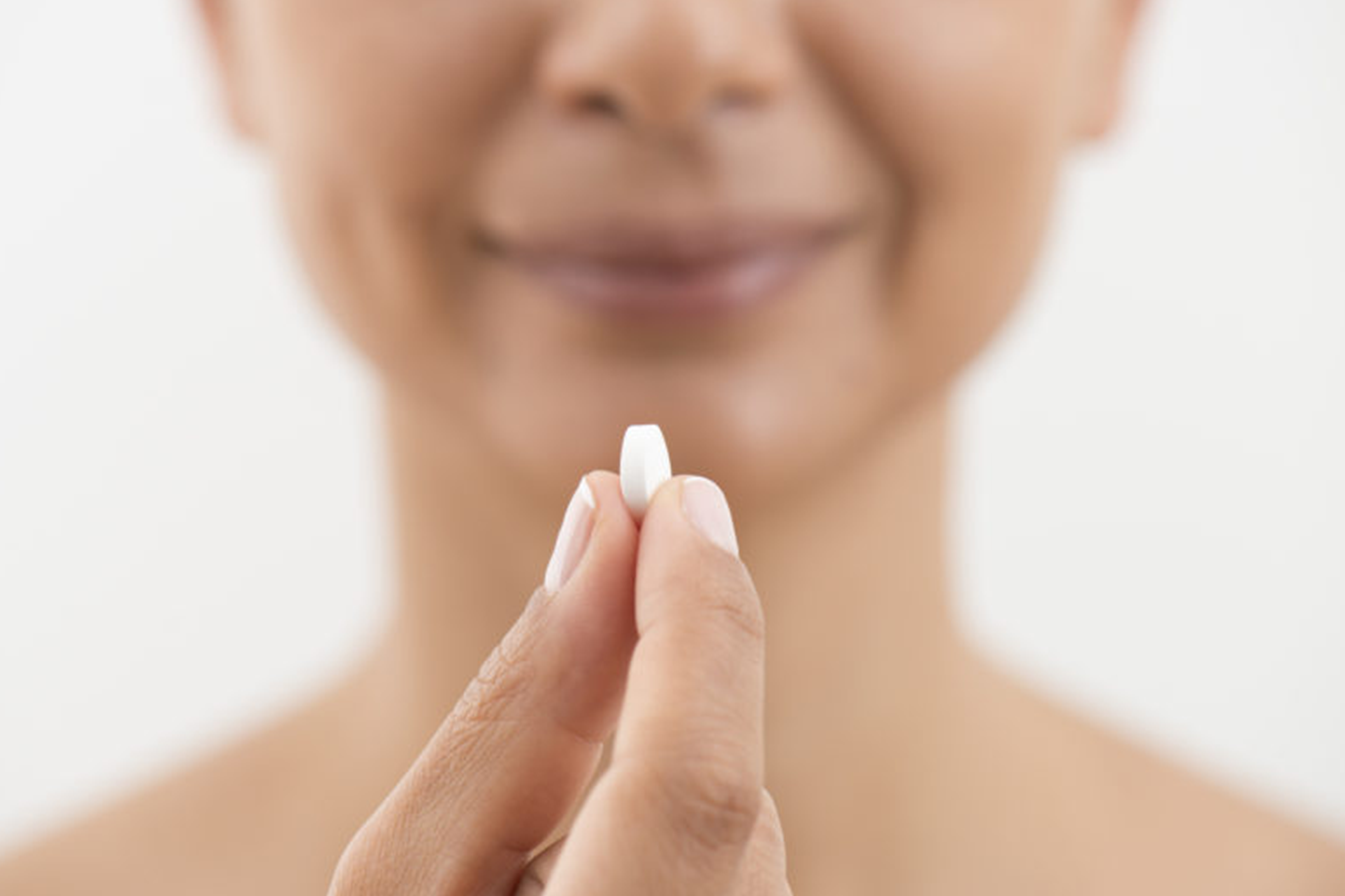 Image of a woman holding a nutrient supplement.