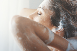 A close up image of a woman shampooing her hair in the shower