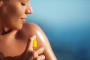 An image of a woman in the sun applying sunscreen.