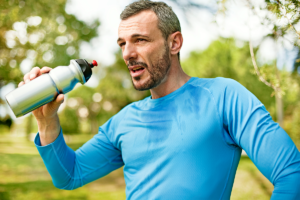 An image of a midster having a drink from a water bottle after doing exercise.