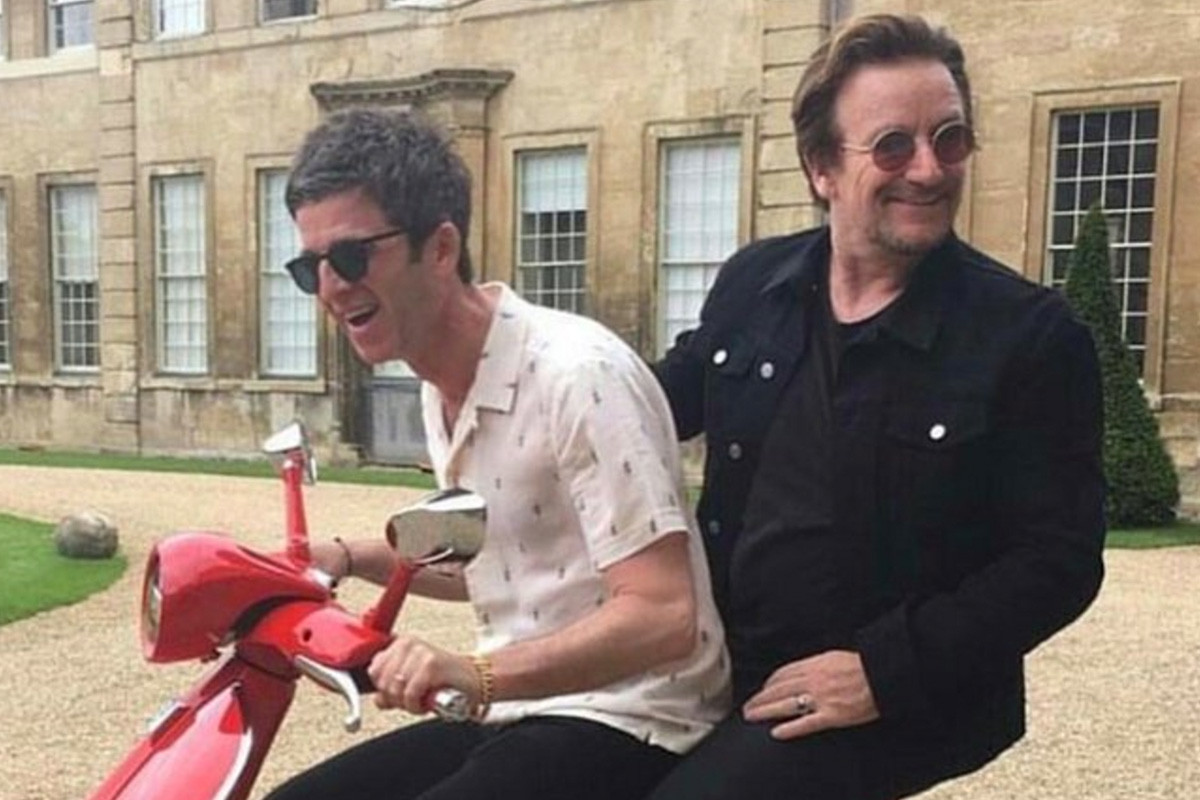 An image of noel gallagher and bono celebrating Noel's 50th on a moped.