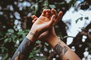 An cropped image of a midster's hands in the air showing off her tattoos.
