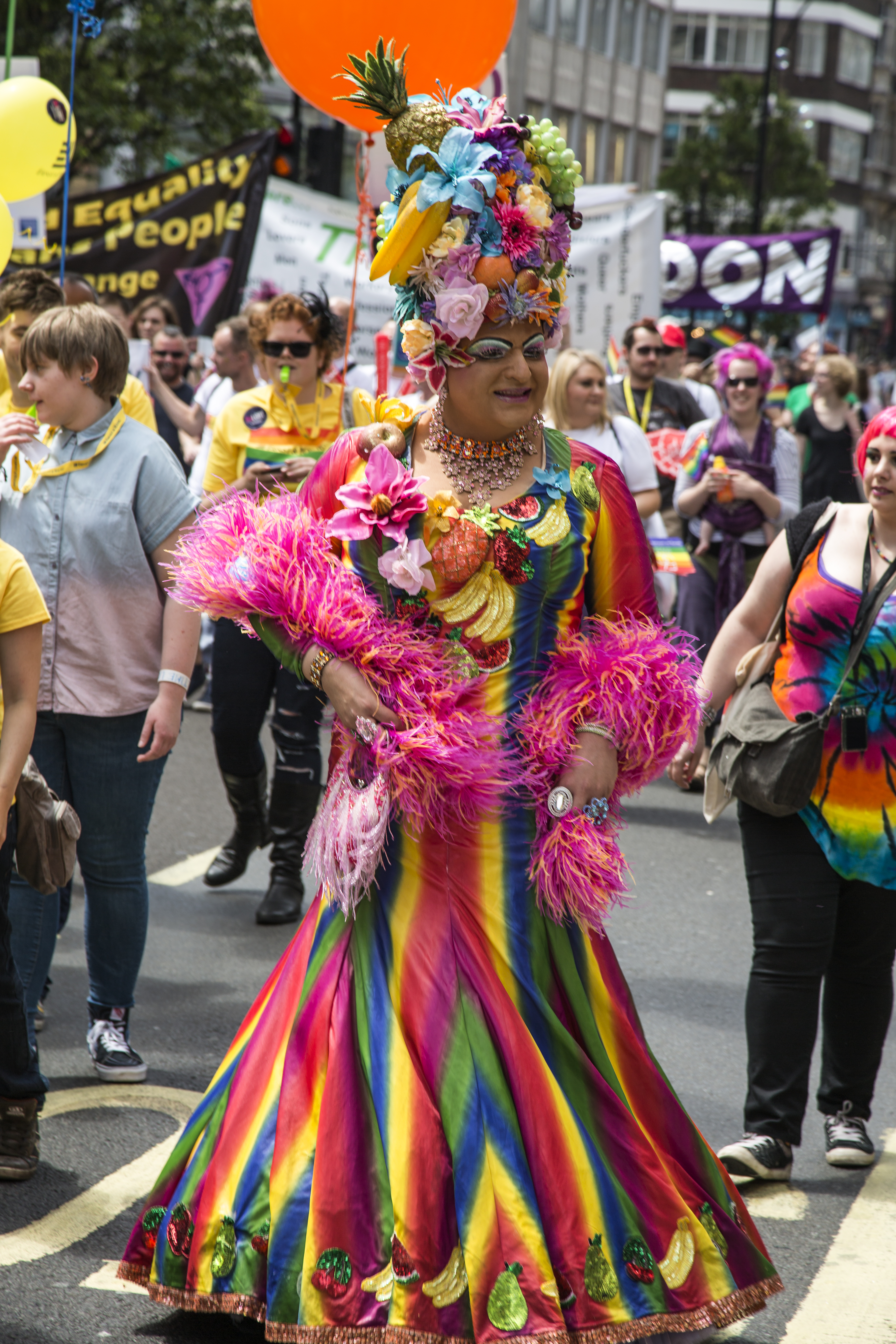 London, United Kingdom - June 29, 2013: A reveller at London Gay Pride 2013 Parade who is dressed in drag with a rainbow coloured dress and a headdress containing tropical fruit