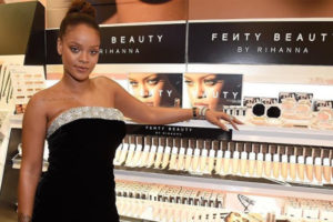 An image of Rihanna standing by her Fenty beauty stand in Sephora