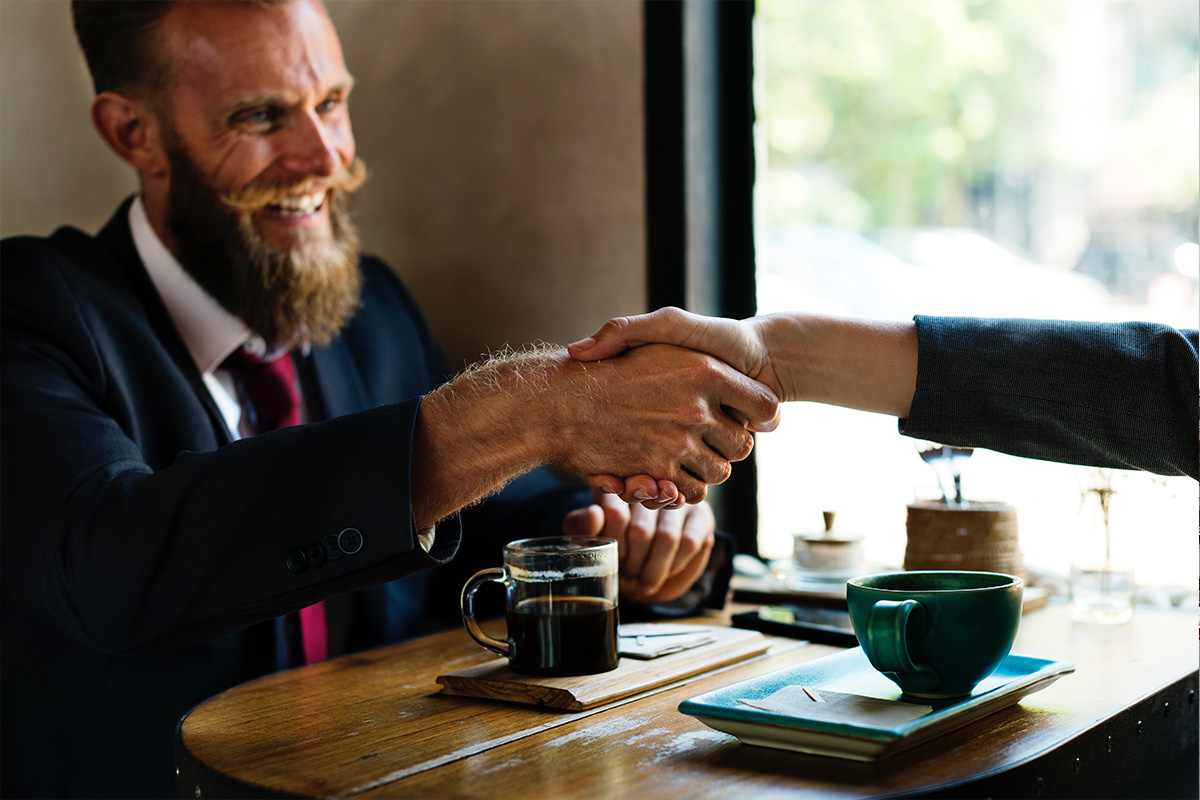 An image oi a middle aged business man shaking hands with his business partner after completing a deal.