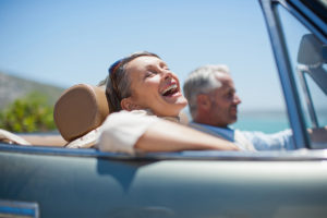 A woman riding in a convertable who is content with her quality of life after taking testosterone.