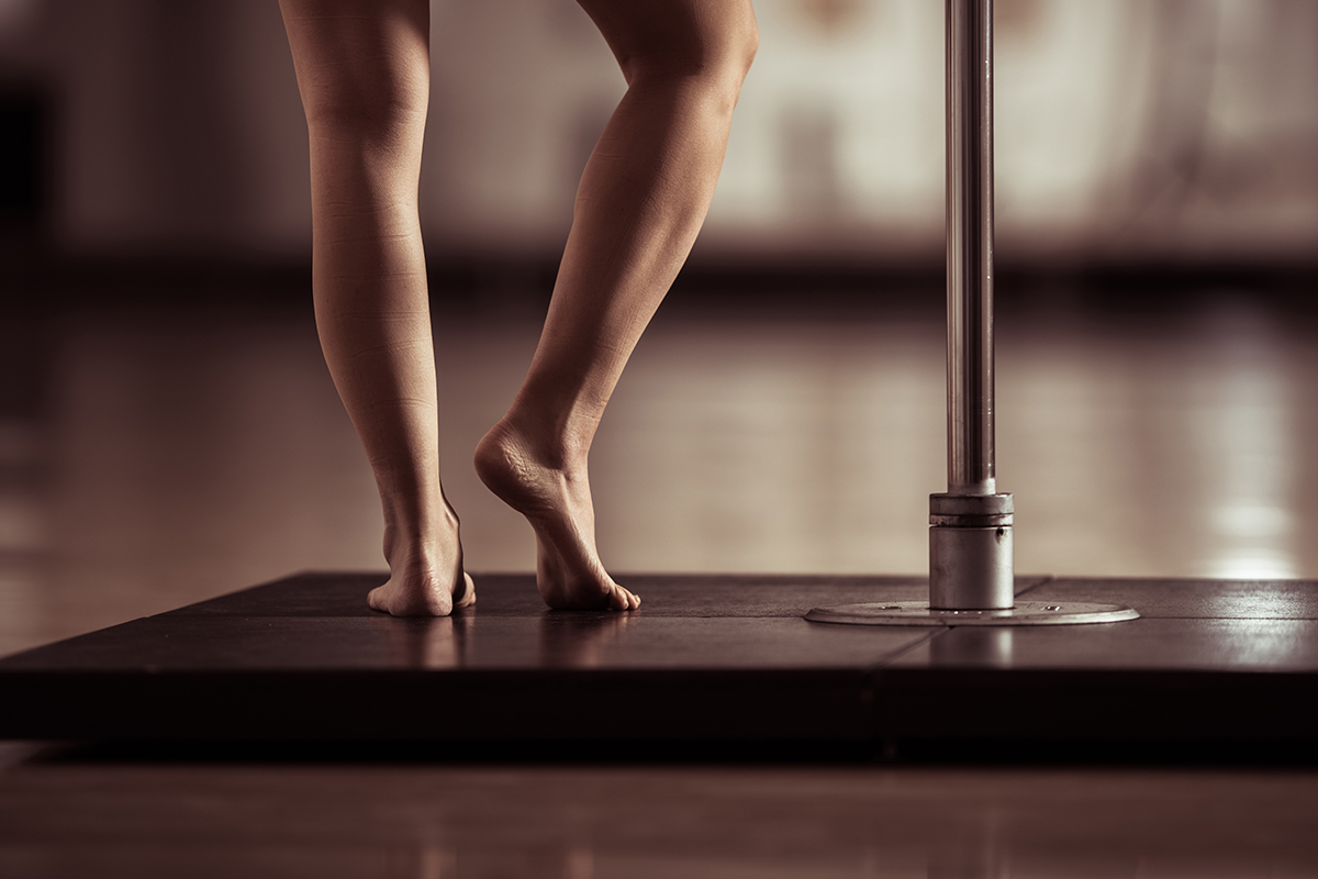 A cropped image of a middle aged woman pole dancing.