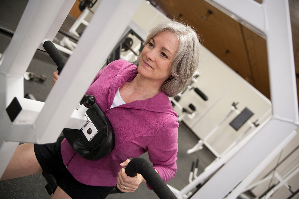 An image of a mature woman new to the gym weight lifting.