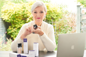 An image of Look Fabulous Forever founder, Tricia Cusden with laptop and her beauty products.