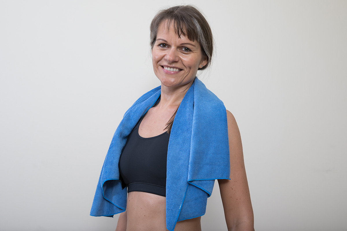 An image of a mature woman smiling in her workout gear.