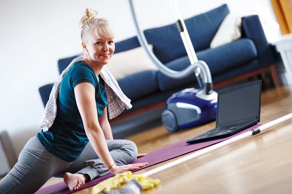 An image of a mature woman working out while cleaning.