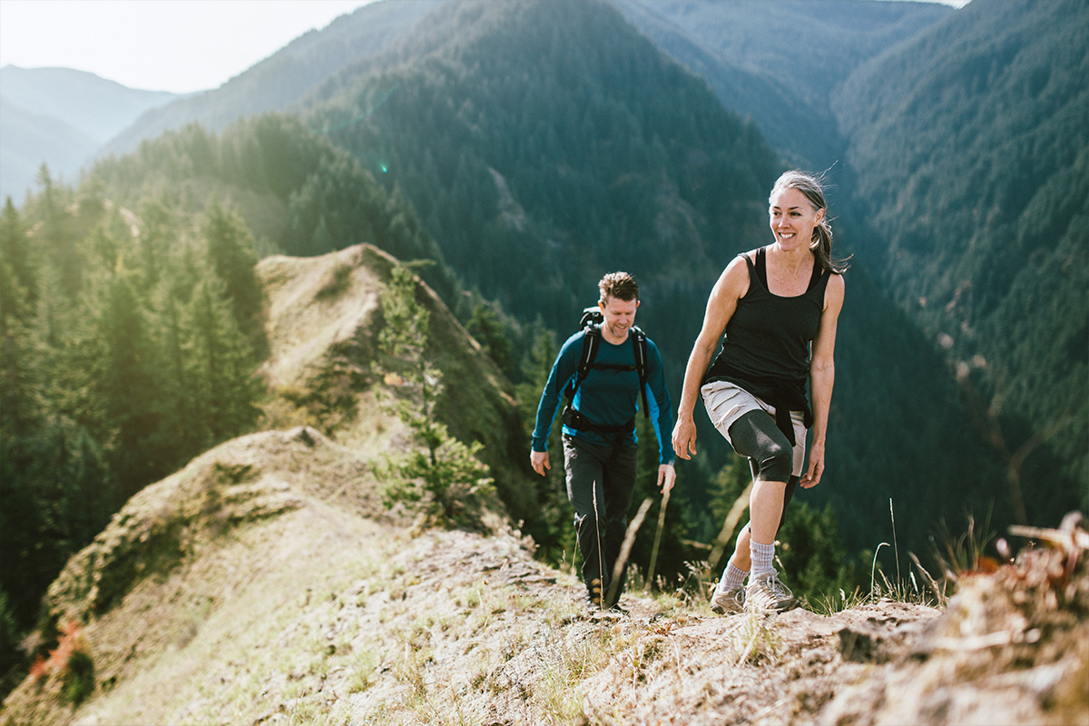 An image of a middle age couple hiking a beautiful green valley.