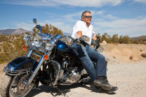 An image of a man in the desert sitting on his motorbike.