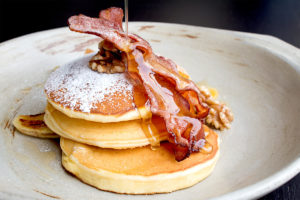 An image of pancakes with two rashers of bacon on top.
