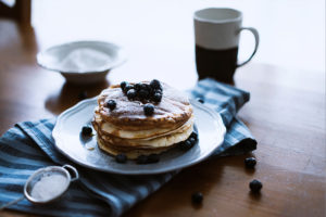 An image of a plate of pancakes with blueberries.