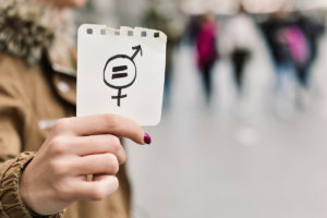 A woman holding up a piece of paper with a women's symbol on it for International Women's Day