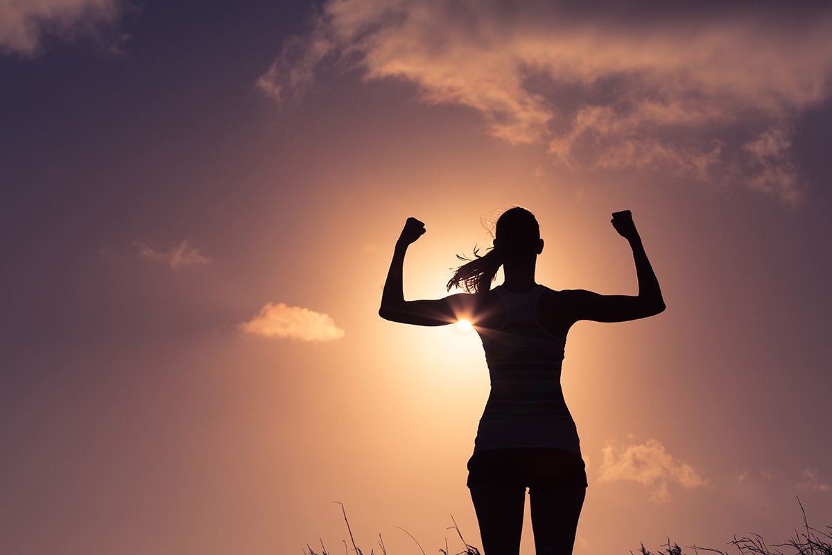 An image of a woman exercising outside in the setting sun.