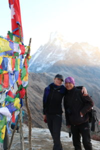 louise backpacking in Nepal with a man with a bandanna and mountains in the background