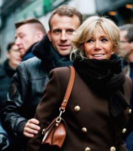 couple walking through a crowd wearing a coat and scarf and the woman is carrying a brown bag
