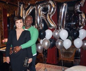 celebrity couple kris Jenner with big silver balloons in background spelling out Kris