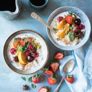 two healthy bowls of fruit and oats on a blue table cloth