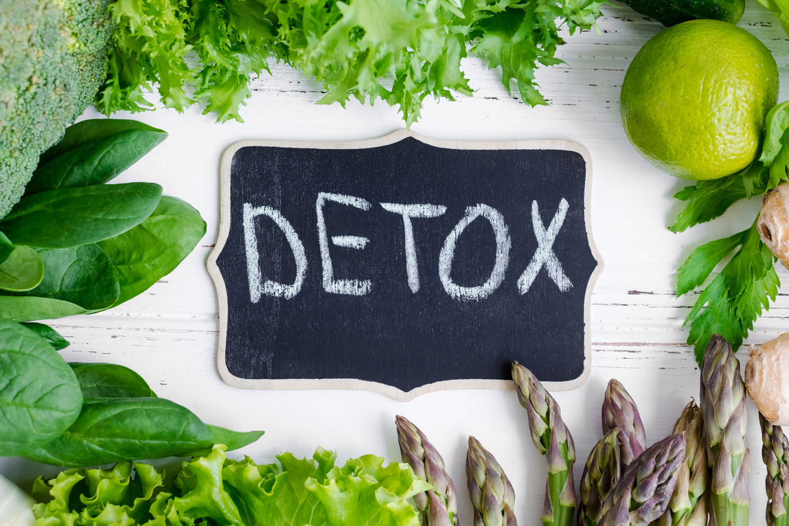detox written ion chalk on a board surrounded by healthy green fruit and veg