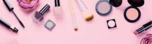 make up and make up tools neatly arranged on a pink background