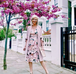 stylish middle aged woman in a floral frill dress on a beautiful London street with blossom out