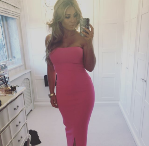 stylish woman in a pink dress taking a photo in full length mirror