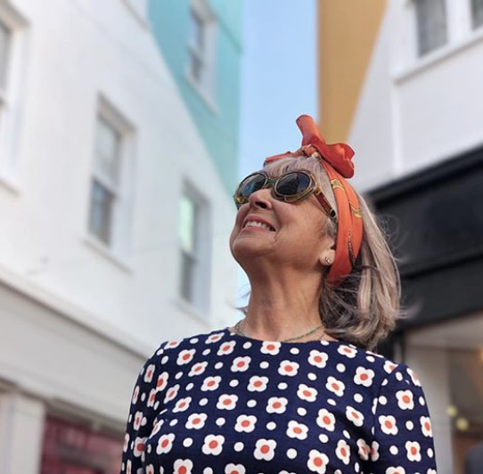 happy stylish middle aged woman looking up at the street