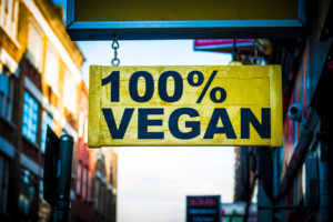 100% vegan wooden yellow sign hanging outside a shop