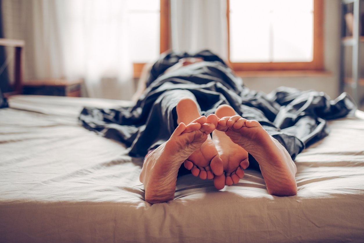 the bare feet of a man and woman in bed together