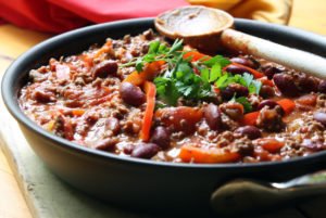 healthy slow cooked chilli in black owl with wooden spoon rested on side