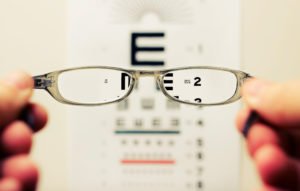 looking through glasses to see the eye test more easily
