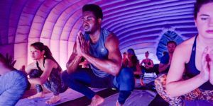 men and women doing yoga pose in a hot pod yoga class