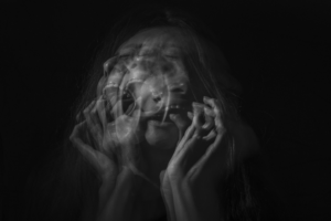 faded overlaid black and white image of a woman screaming holding her face