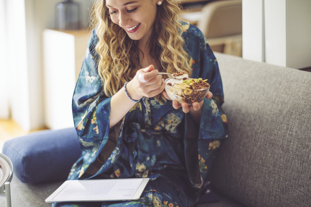 woman sat on the sofa eating healthy breakfast