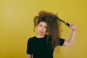woman struggling with her hair, combing it with a rake