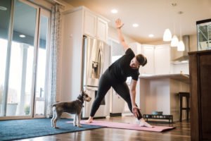 woman doing yoga in her kitchen with her dog
